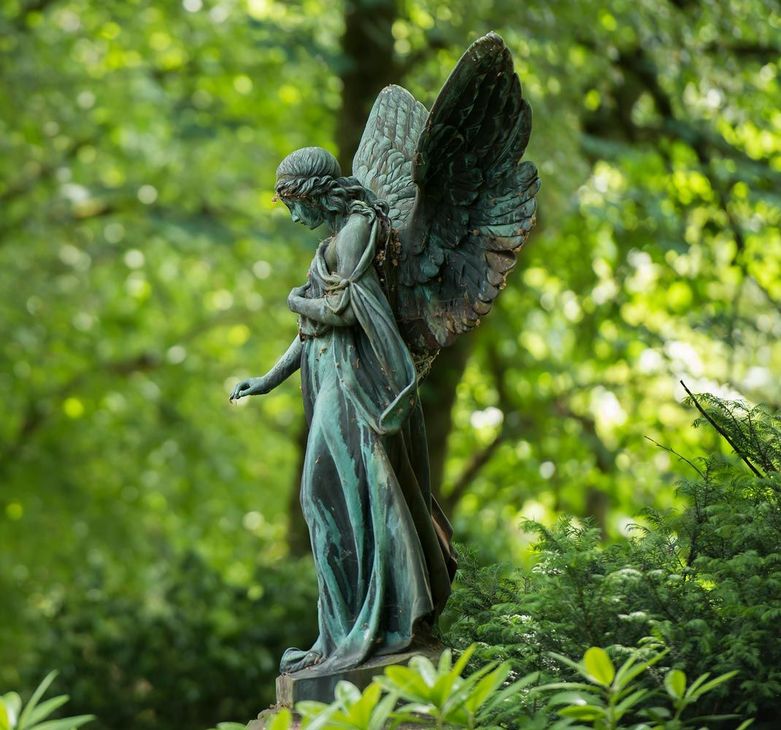 Eine Engelsstatue steht mitten in einem Wald.
