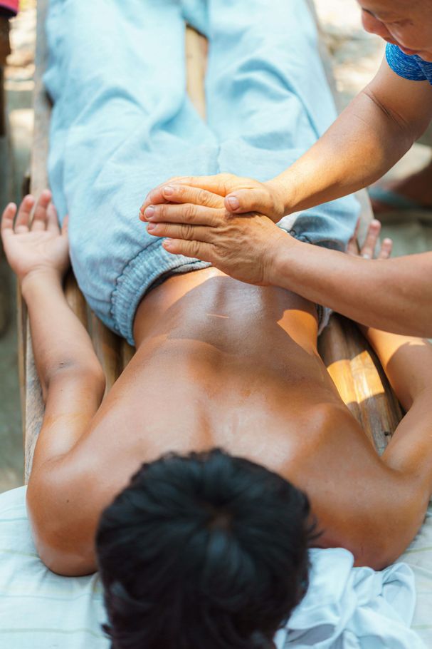 Ein Physiotherapeut untersucht die Schulter und den oberen Rücken eines Patienten auf Schmerzen oder Bewegungseinschränkungen.