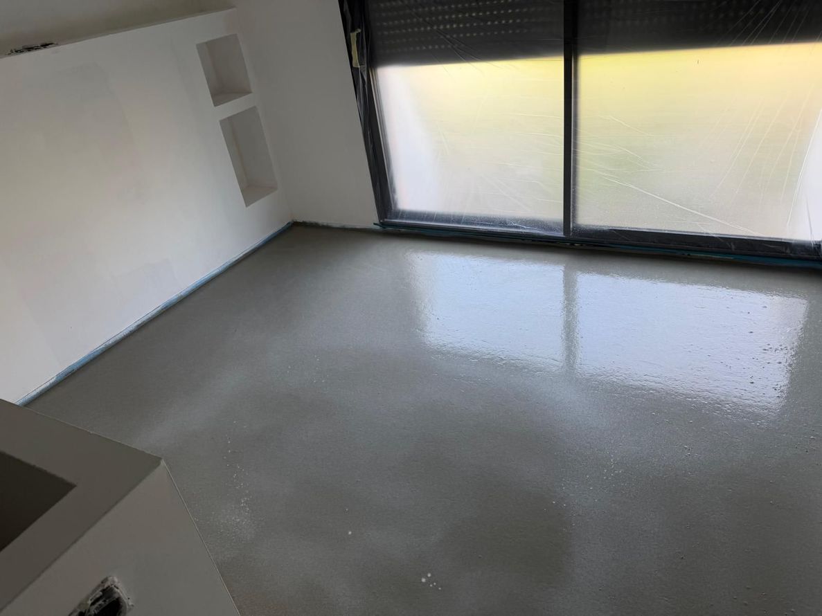 Pièce vide avec un sol gris brillant et des portes coulissantes en verre dépoli laissant passer une lumière jaune.