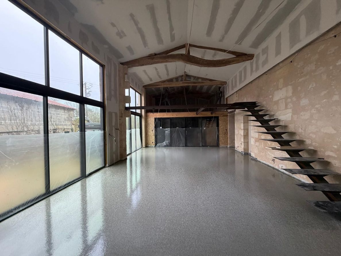 Intérieur de loft moderne avec de grandes fenêtres, un escalier en mezzanine et une chape fluide.