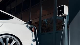 Weißes Elektroauto wird neben einem weißen EV-Ladegerät aufgeladen.