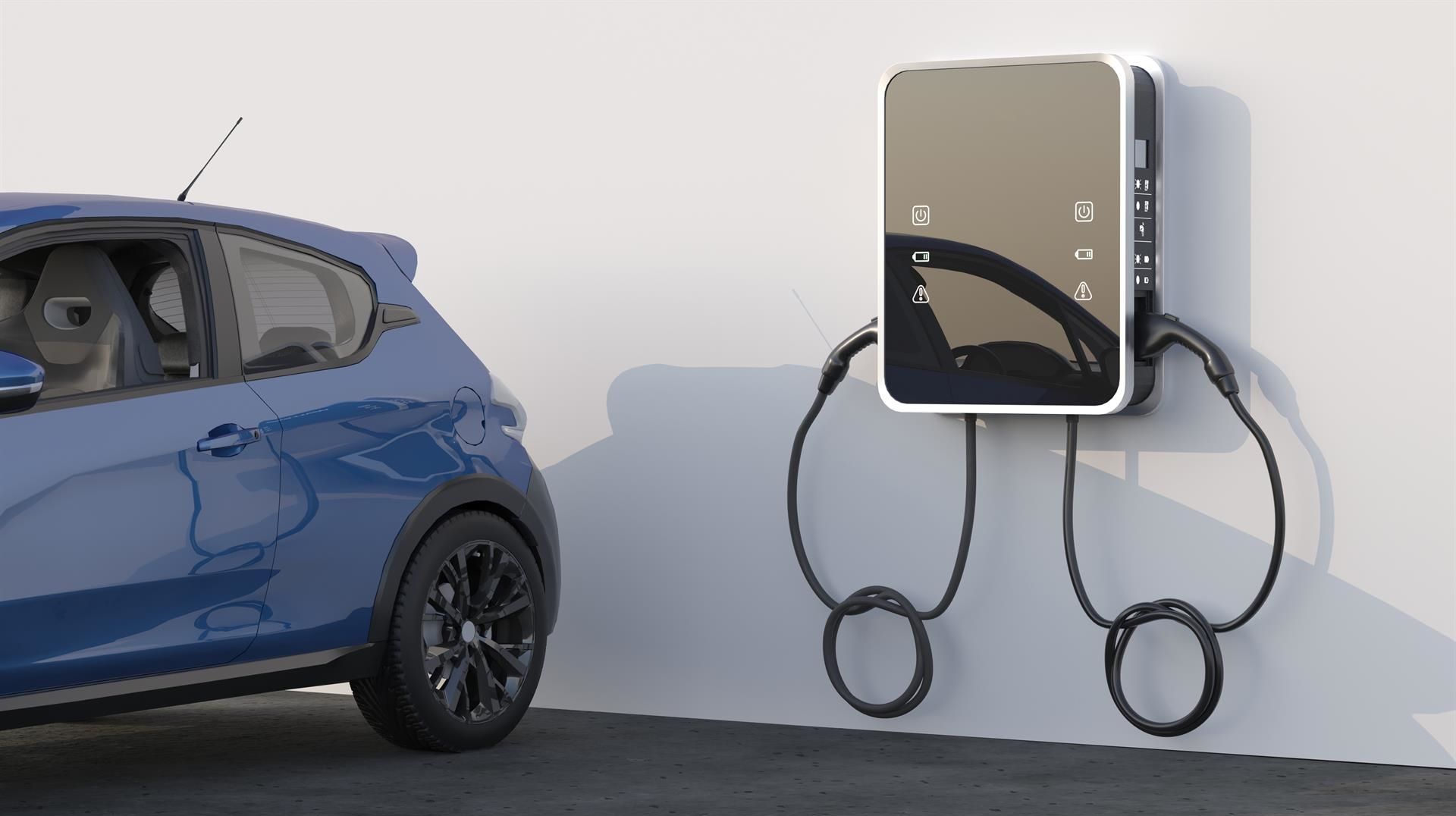 Blaues Elektroauto wird an einer wandmontierten Ladestation aufgeladen.