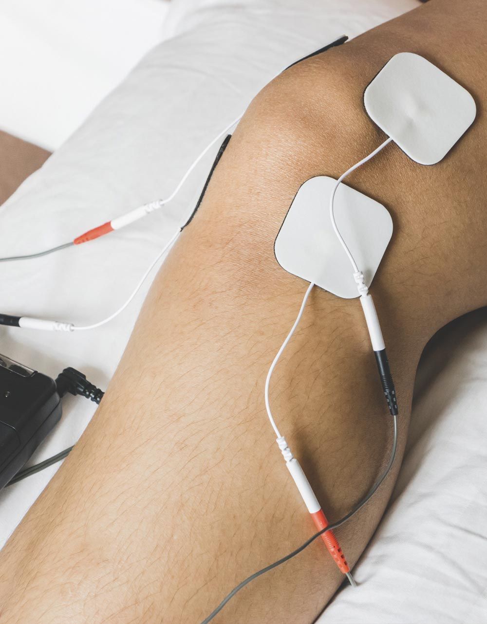 Una persona está acostada en una cama con electrodos en la pierna.