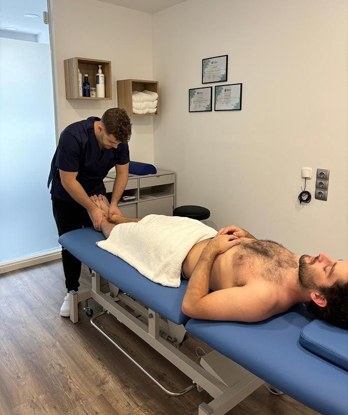 Un hombre está acostado en una cama recibiendo un masaje de un médico.