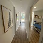 Un largo pasillo con suelos de madera y un cuadro en la pared.