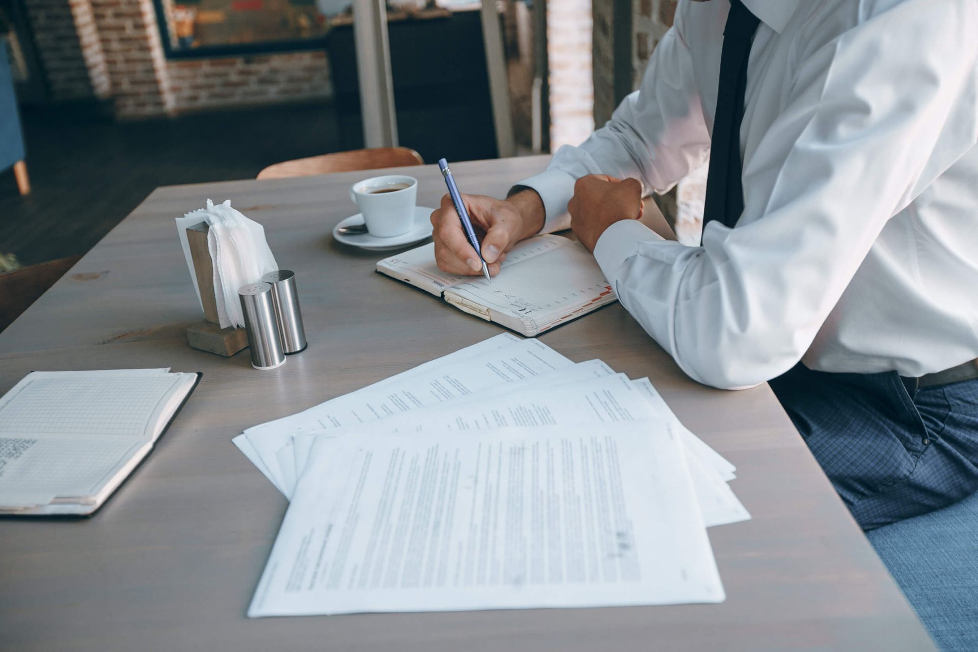Un hombre está sentado en una mesa escribiendo en un cuaderno.
