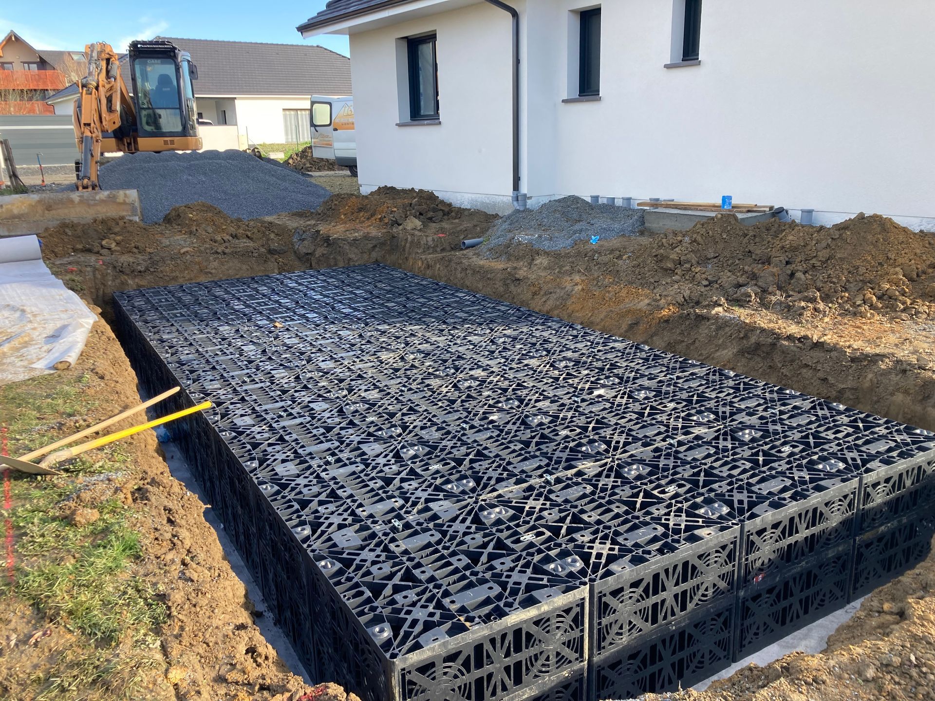 Un bassin de régulation d'eaux pluviales, en cours d'installation près d'une maison.