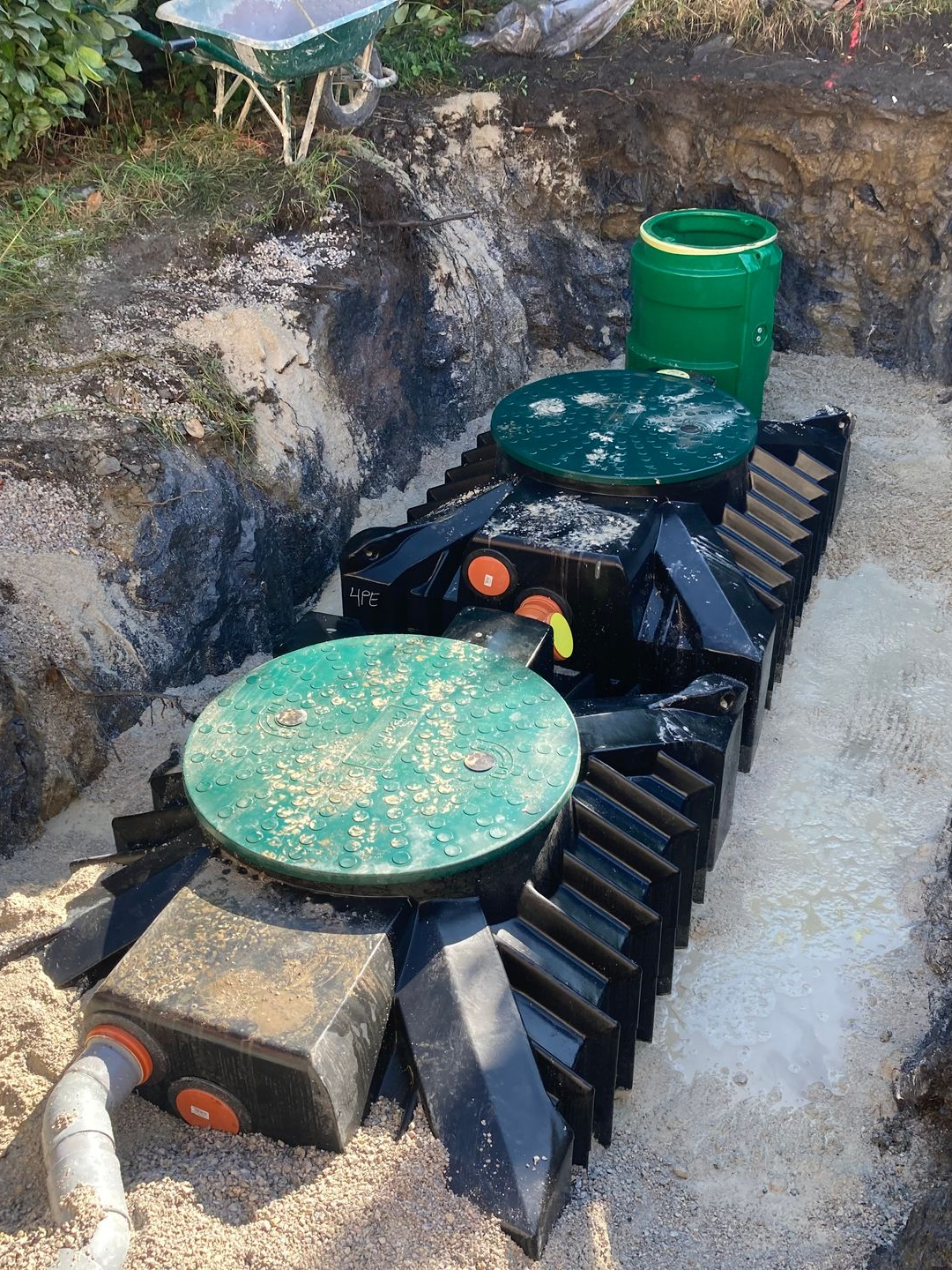 Installation d'un système de fosse septique dans une tranchée, comprenant des réservoirs et des tuyaux.