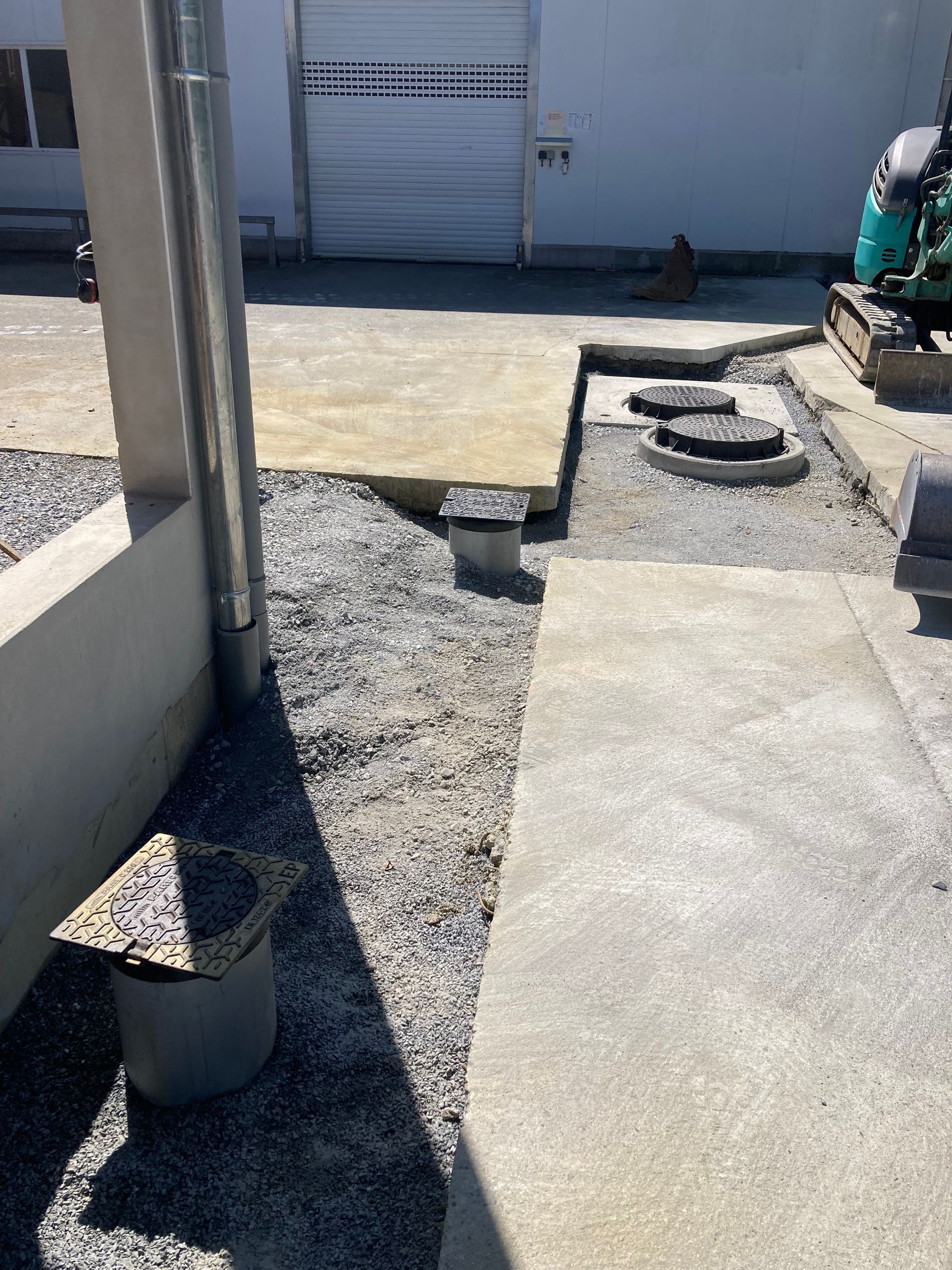 Vue extérieure d'un chantier de construction avec des allées en béton, du gravier et des points d'accès aux services publics.