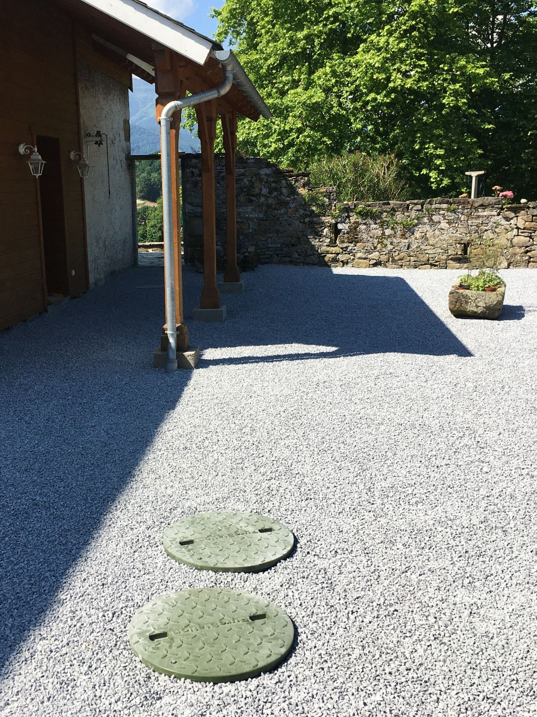 Cour gravillonnée avec deux couvercles circulaires verts.