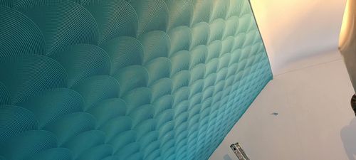 Plafond texturé bleu sarcelle, mur blanc et lumière chaude dans le coin.