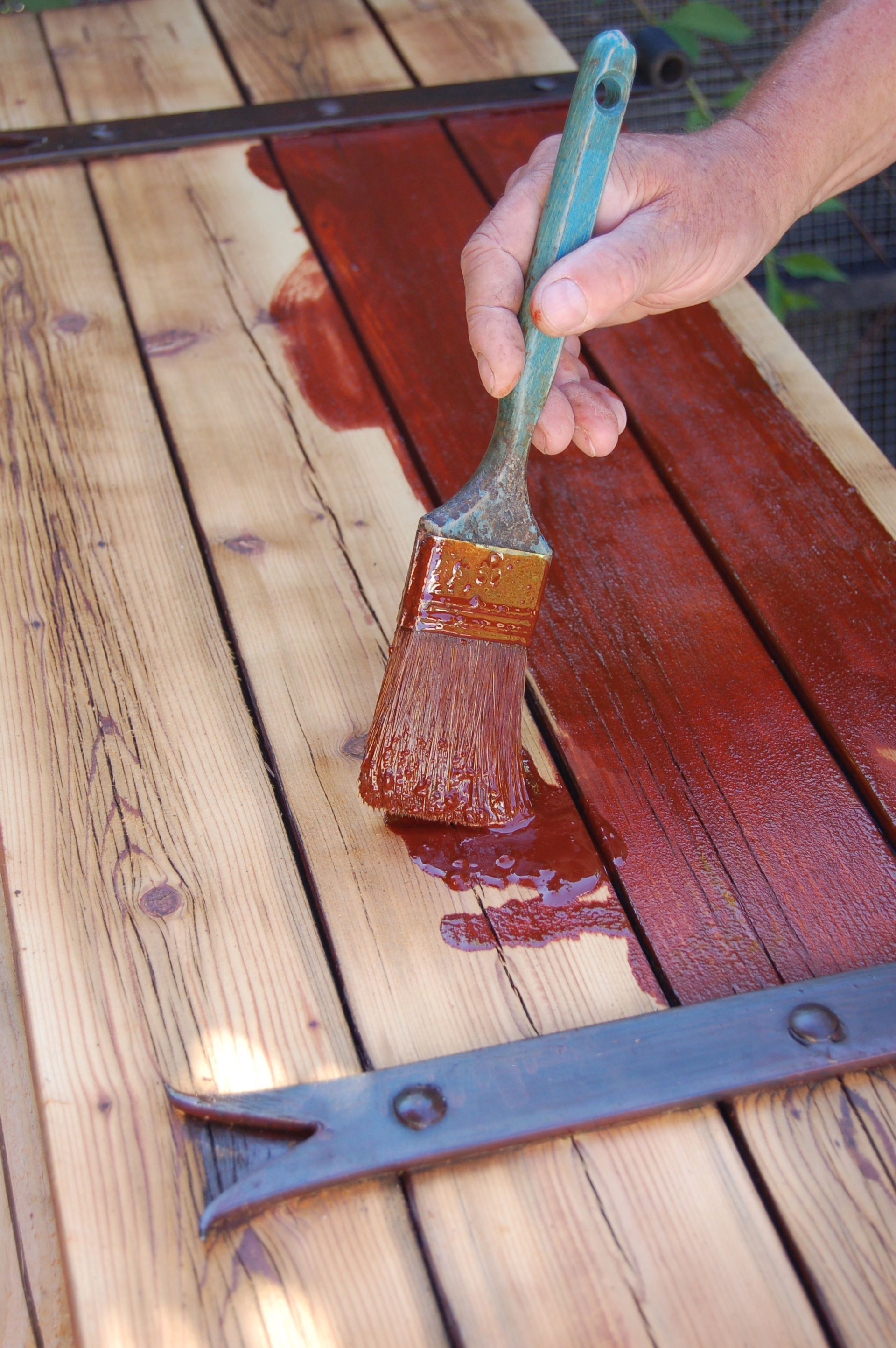Peindre une surface en bois au pinceau, appliquer une teinture ou une peinture rouge à proximité d'un outil en métal.
