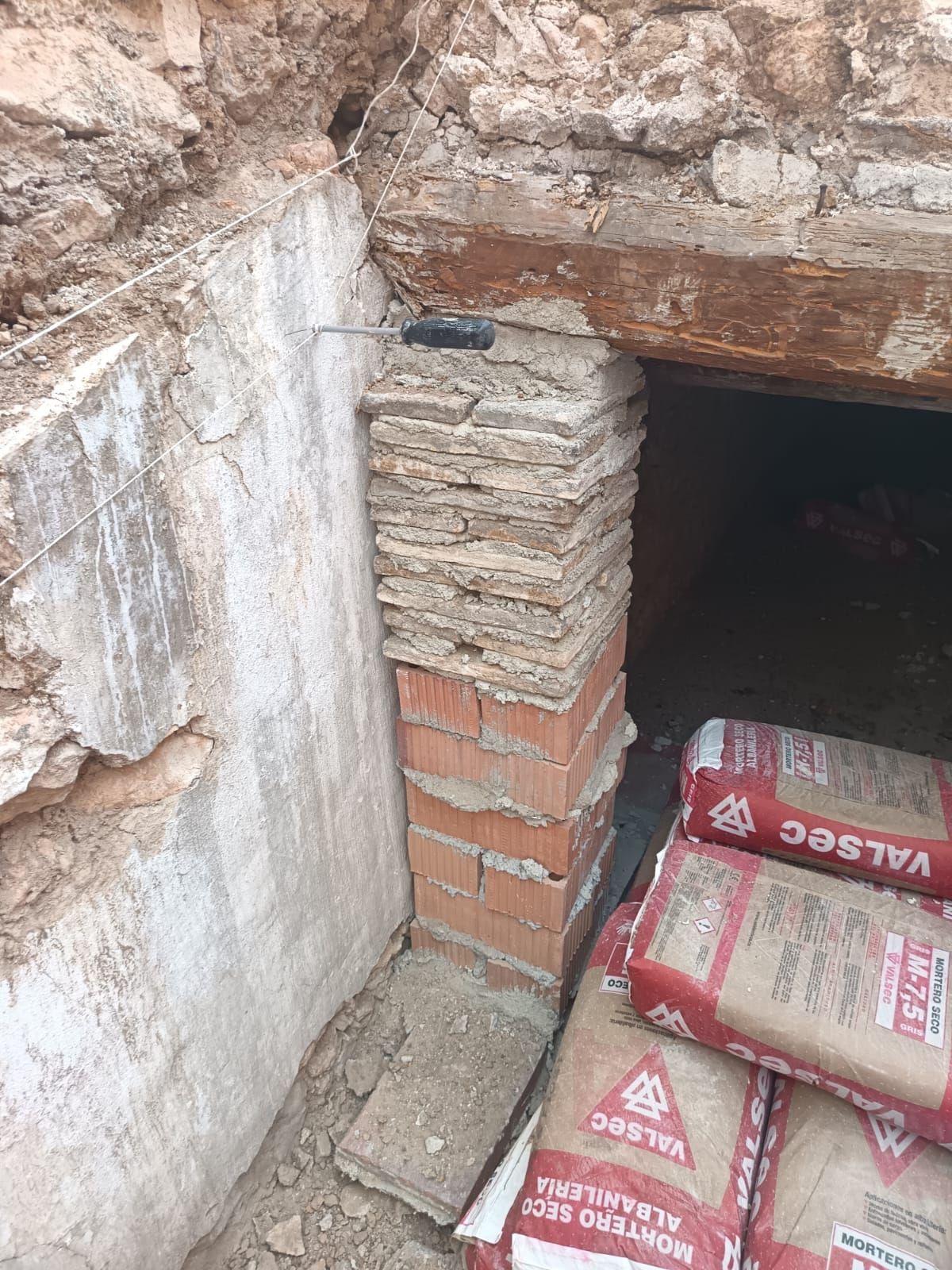 Una pila de bolsas de cemento junto a una pared de ladrillos.