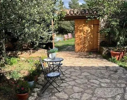 Un patio de piedra con una mesa y sillas frente a una puerta de madera.