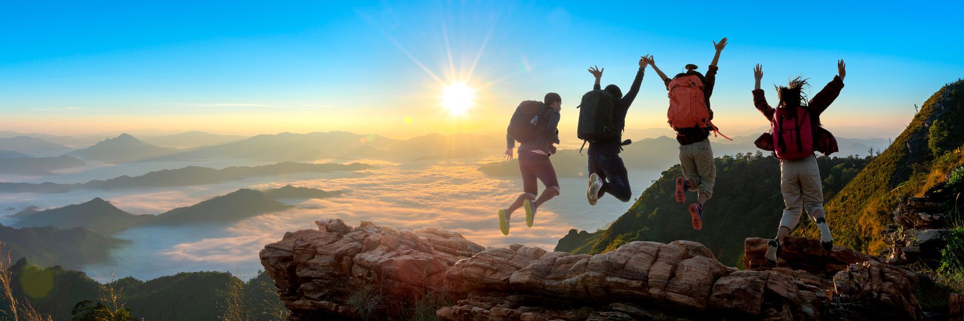 Groupe de personnes qui sautent avec une vue panoramique sur les montagnes