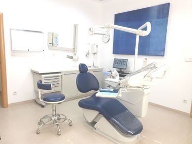 Consultorio dental con sillón dental azul y blanco, luz y gabinetes.