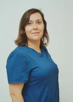 Mujer con cabello castaño con un top azul, mirando hacia la cámara, contra un fondo blanco.
