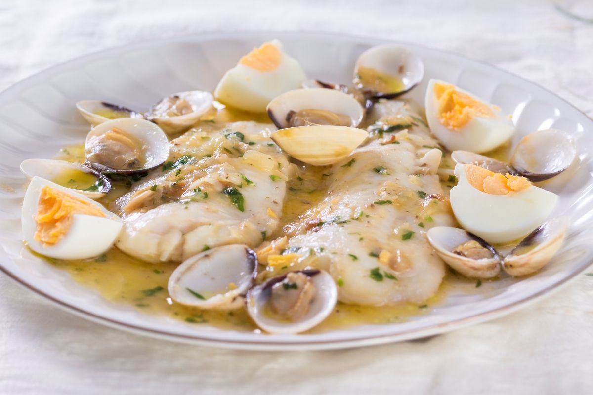 Un plato de comida y una copa de vino en una mesa.
