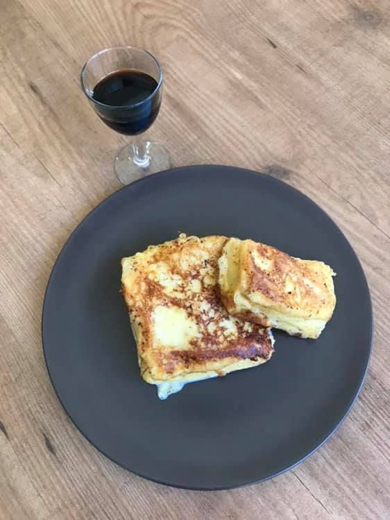 Un plato de comida y una copa de vino en una mesa.
