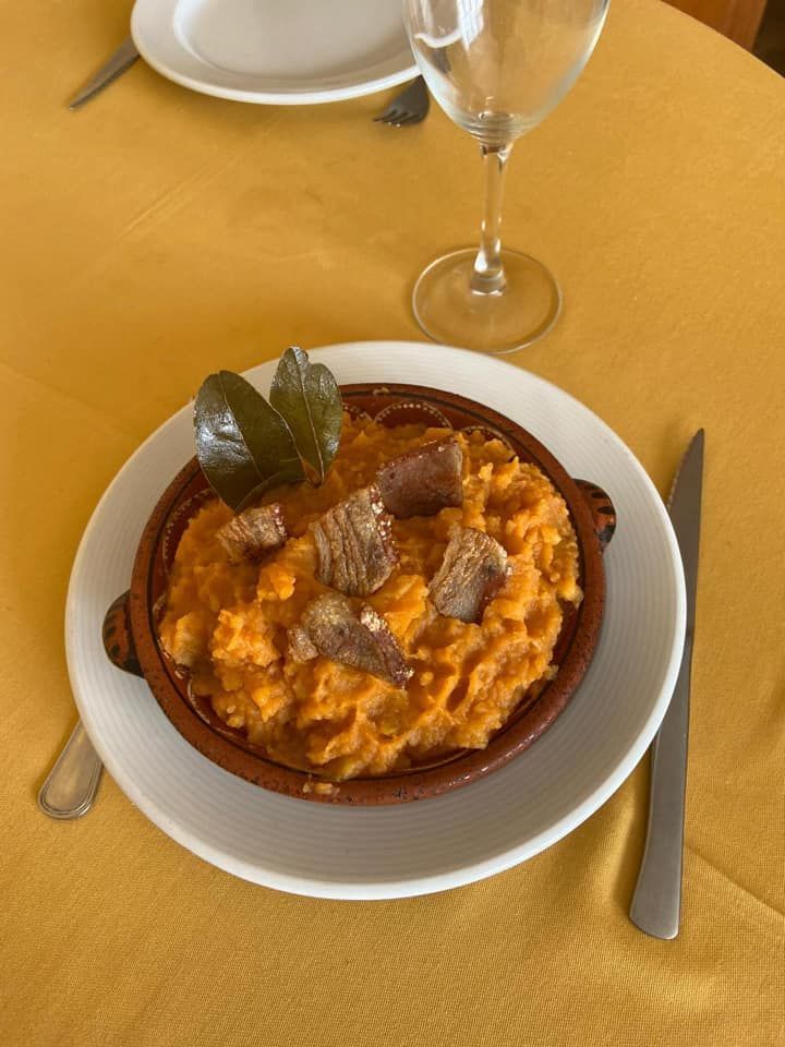 Un plato de comida está en un plato sobre una mesa al lado de una copa de vino.