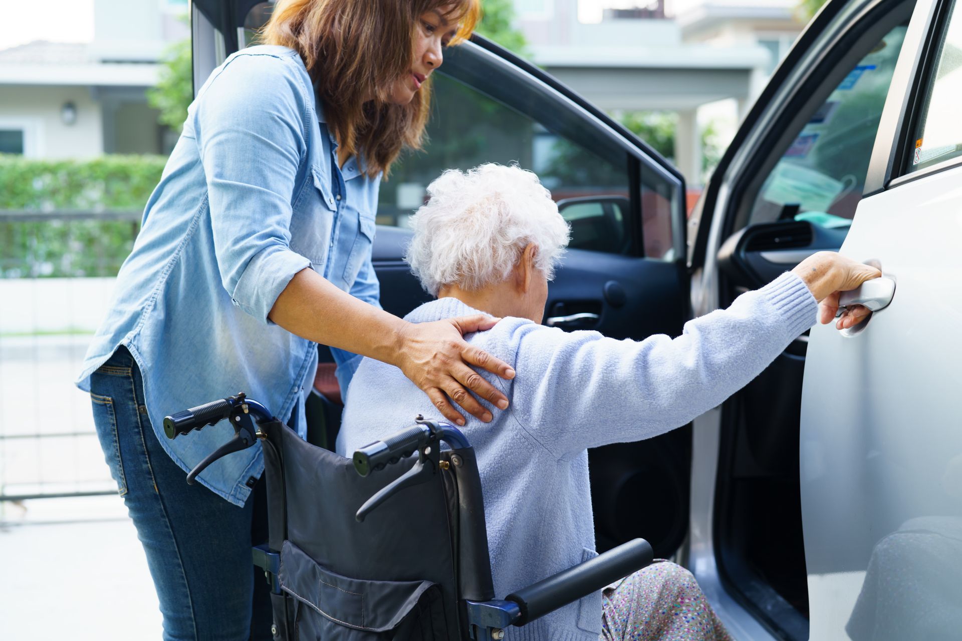 Une femme âgée en fauteuil roulant qui monte dans une voiture