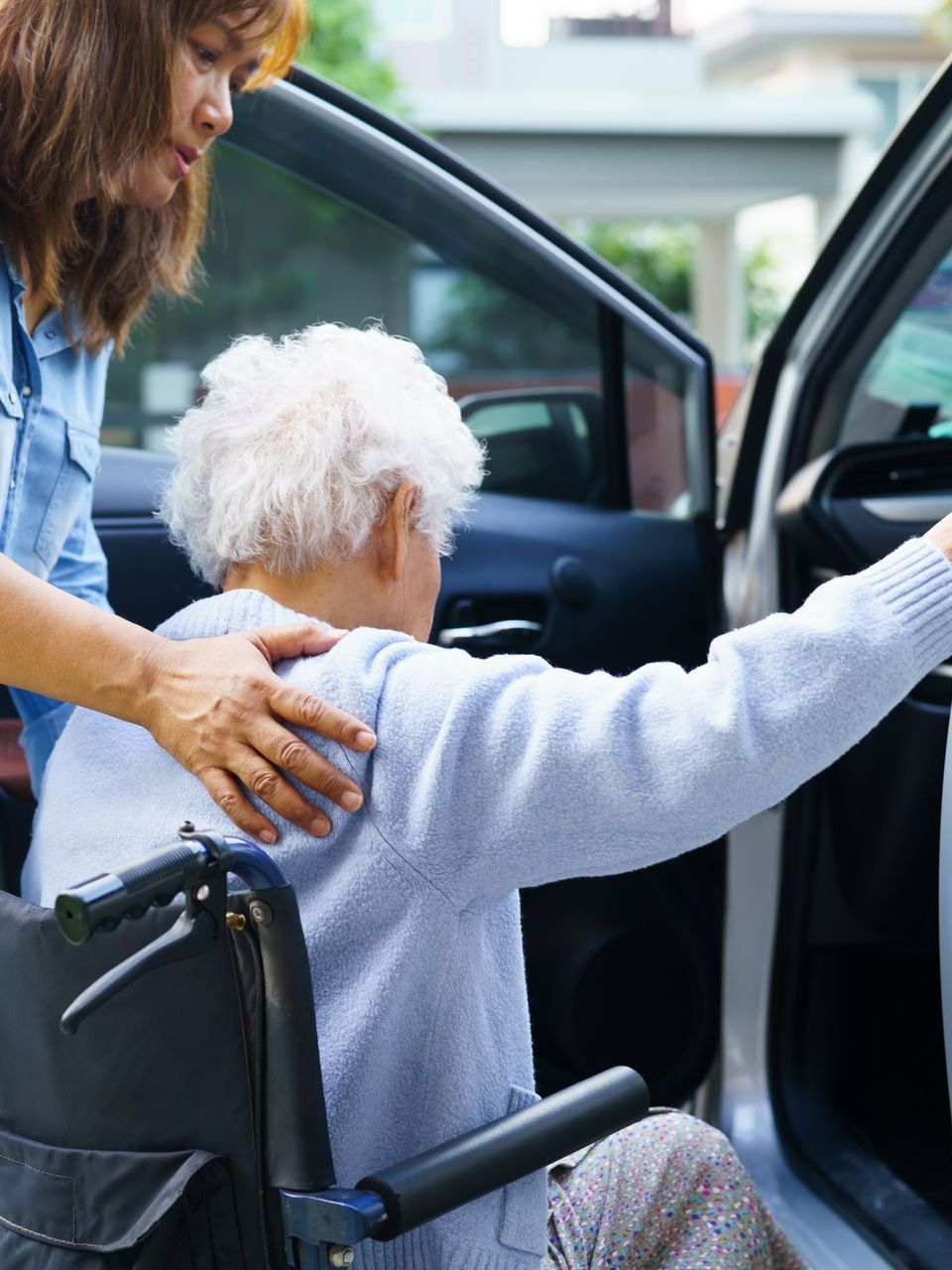 Une femme qui aide une personne âgée à entrer dans une voiture