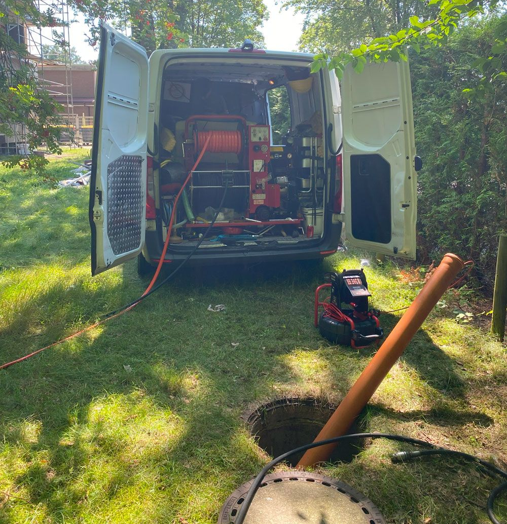 Ein Mann arbeitet an einem Abfluss in einem Badezimmer neben einem Waschbecken.