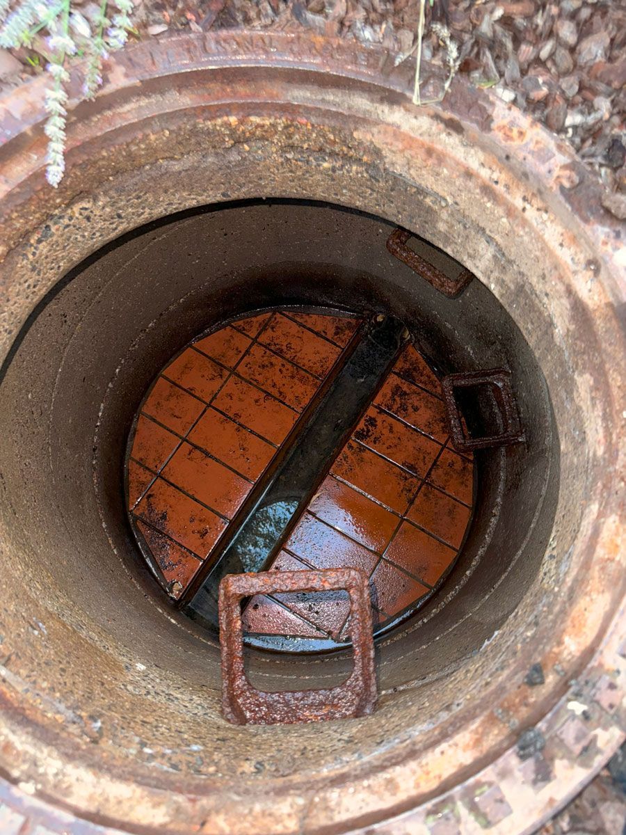 Ein Mann arbeitet an einem Abfluss in einem Badezimmer neben einem Waschbecken.