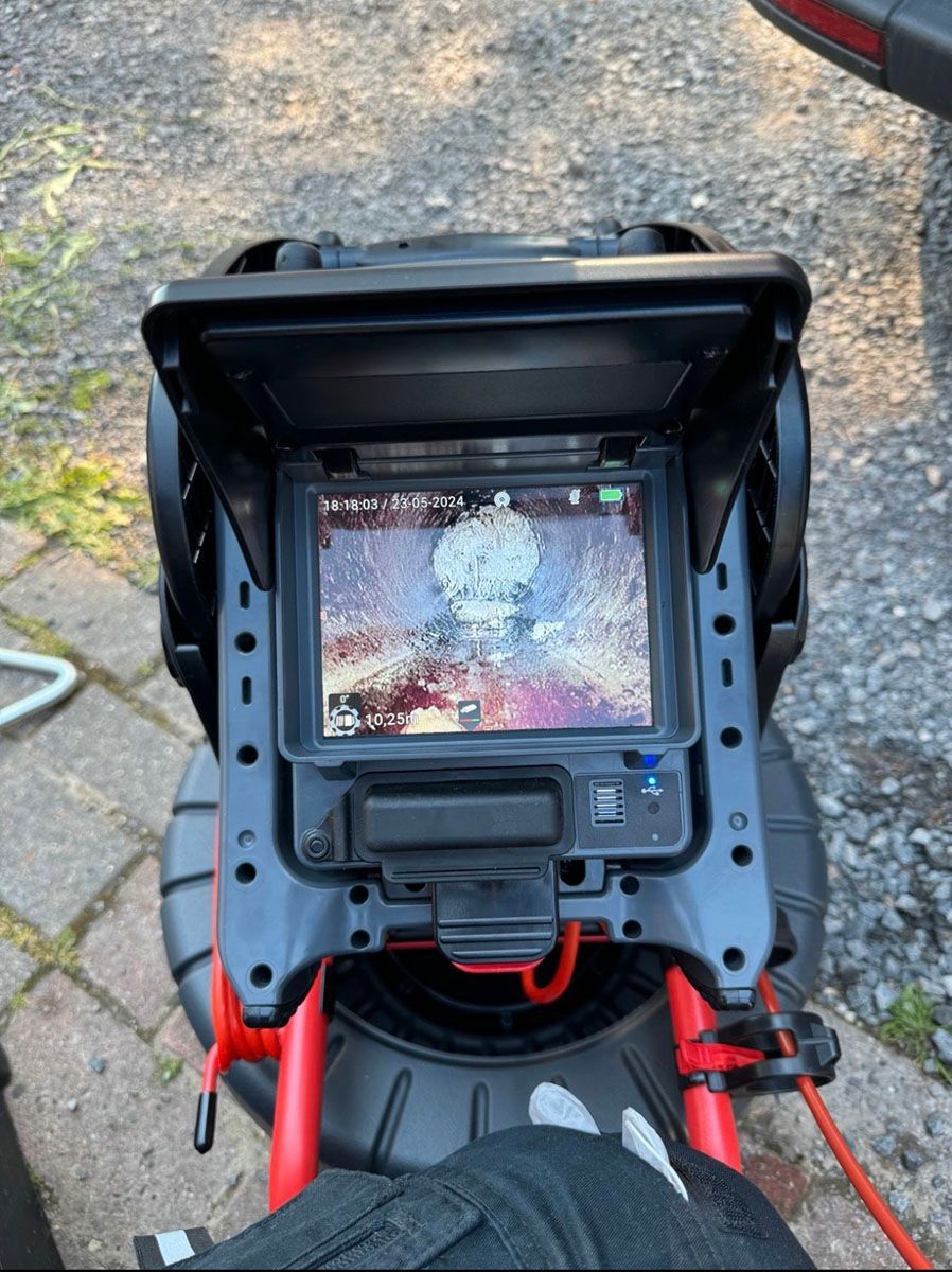 Eine Person benutzt eine Kamera, um ein Foto von einem Rohr zu machen.