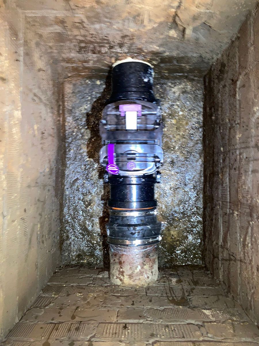 In der Mitte einer Backsteinmauer liegt ein großes Rohr.