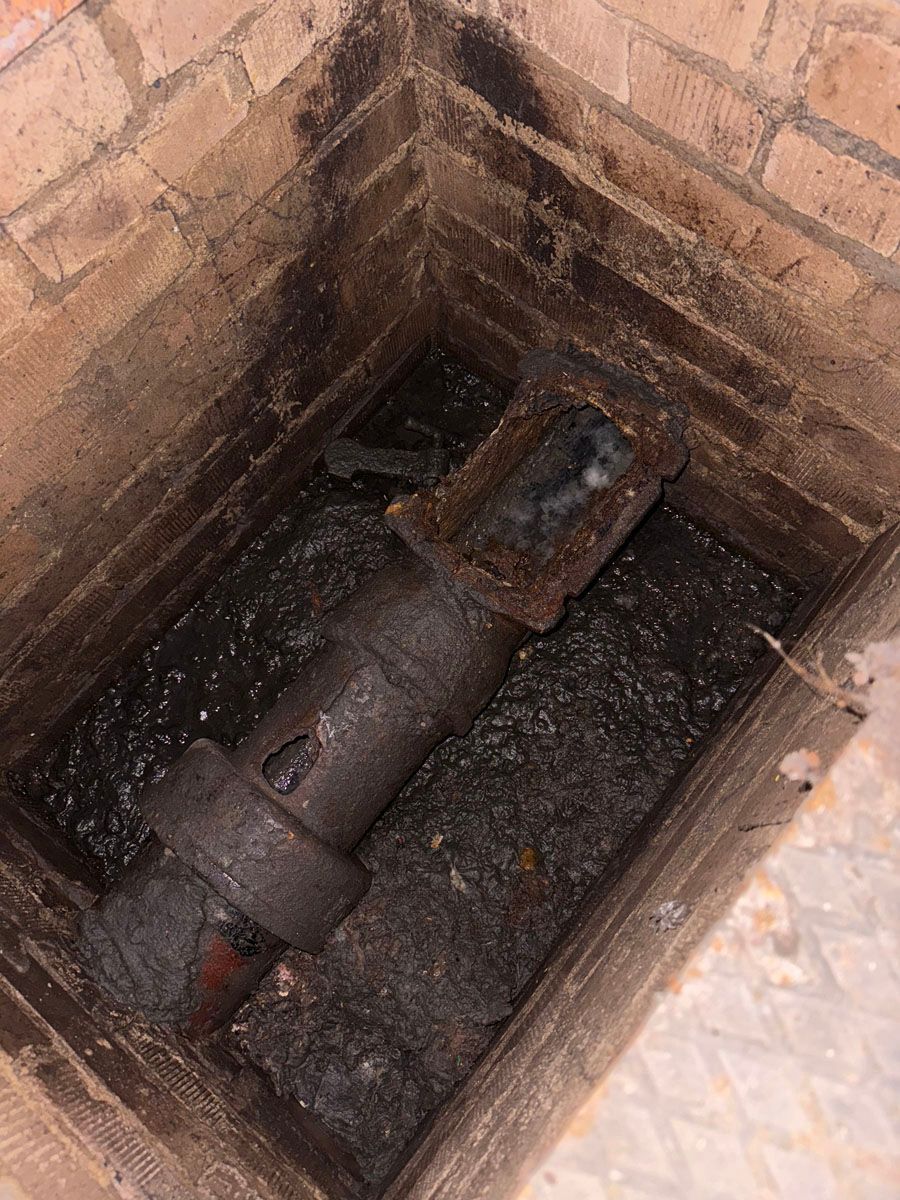 Ein rostiges Rohr steckt in einem Loch in einer Backsteinmauer.