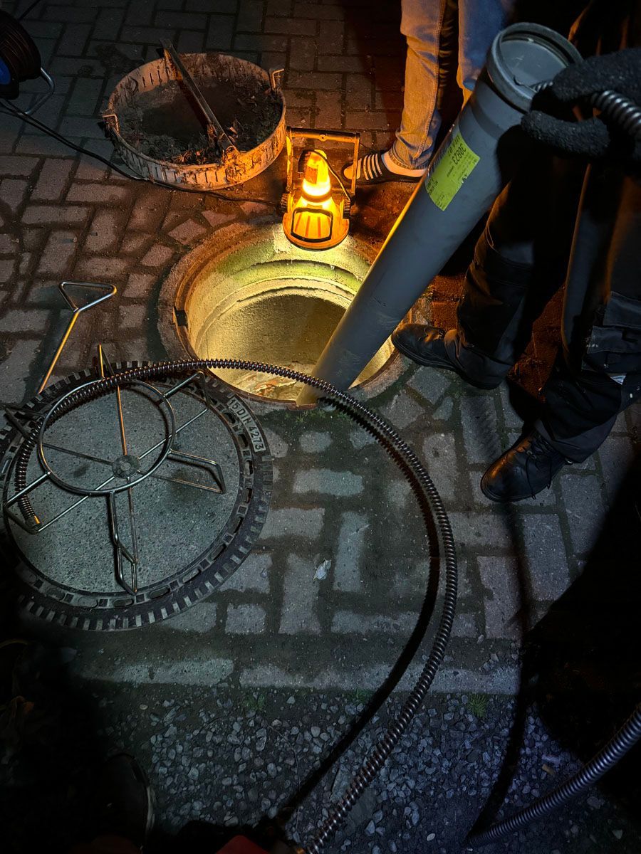 Ein Kanaldeckel wird nachts von einer Person geöffnet.
