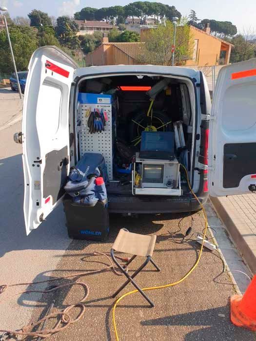 La parte trasera de una camioneta de servicio blanca está abierta, dejando al descubierto herramientas y equipos; hay una silla instalada.