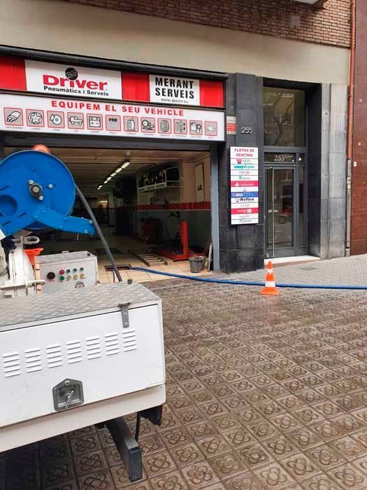 Exterior de un taller de neumáticos con un camión al frente. Un cartel rojo y blanco dice