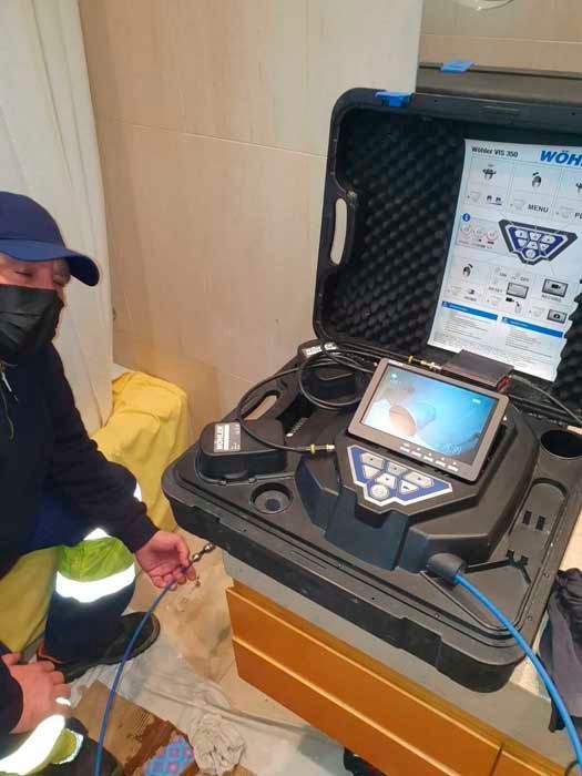 Hombre que utiliza un sistema de inspección con cámara para examinar las tuberías en el interior.