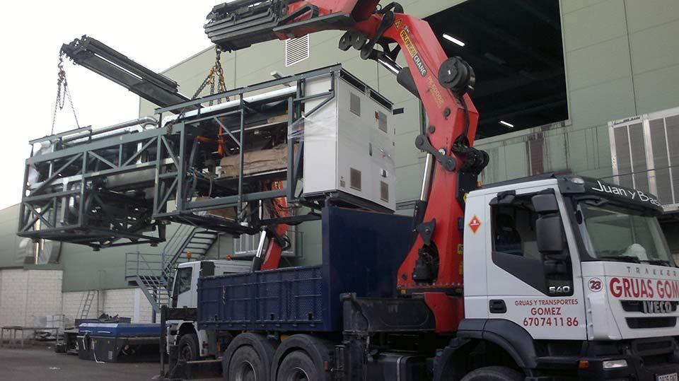 Una grúa está levantando un edificio y subiéndolo a un camión.