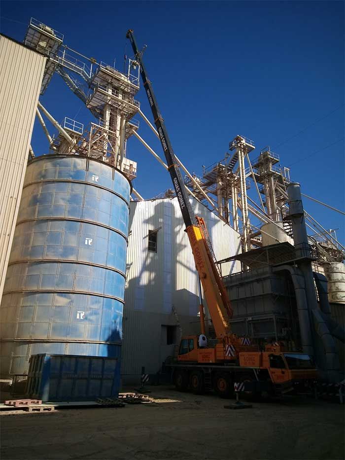 Una gran grúa está sentada frente a un gran edificio.