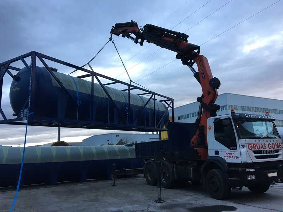 Un camión con una grúa acoplada está levantando un tanque grande.