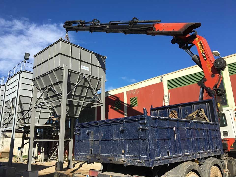 Un camión con una grúa acoplada está estacionado delante de un edificio.