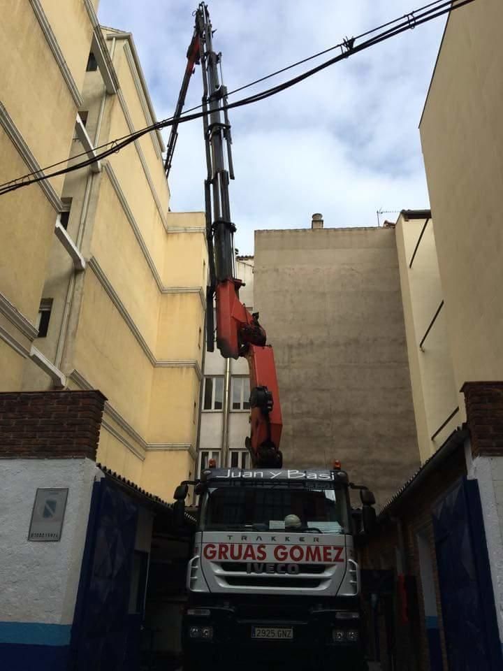 Un camión de la Grúa Gómez está estacionado frente a un edificio.