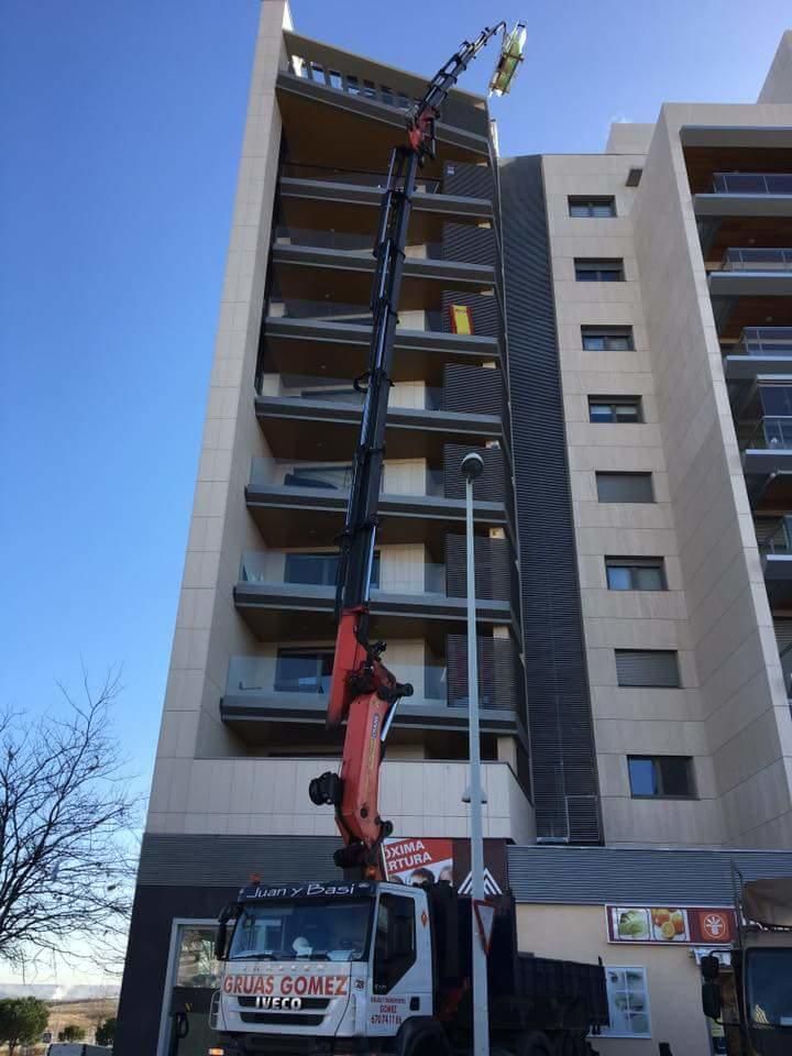 Una grúa está fijada al costado de un edificio alto.