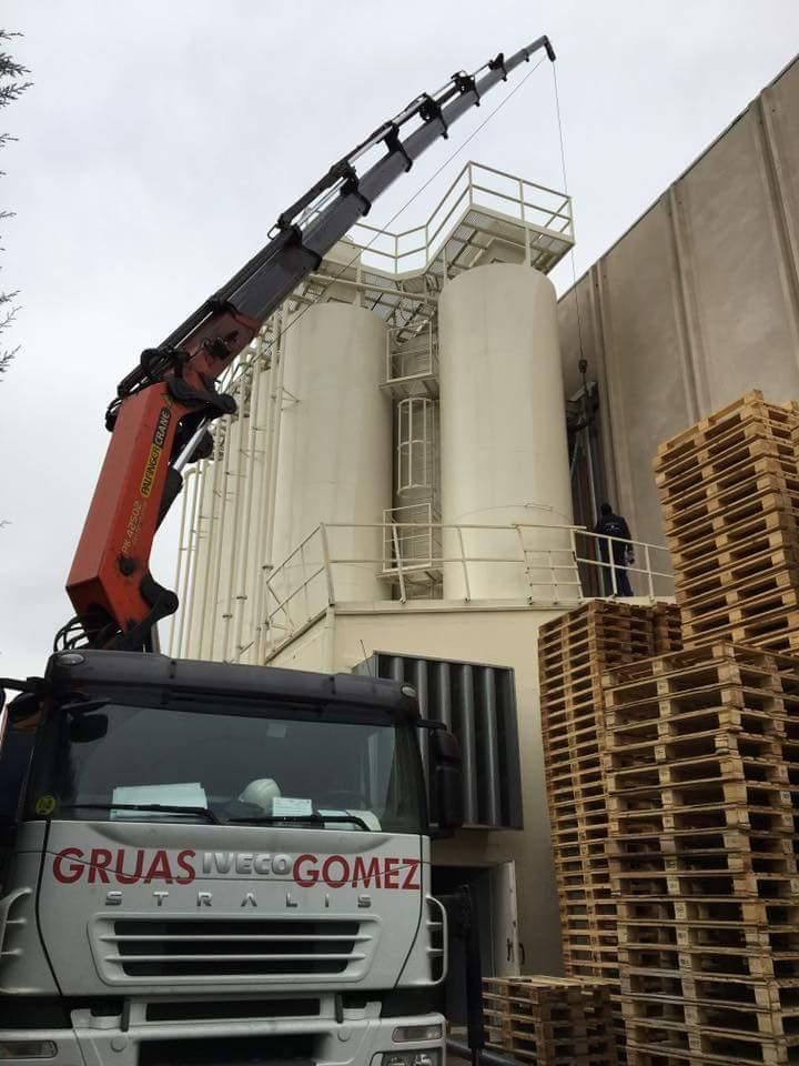 Un camión con una grúa encima está estacionado frente a un edificio.