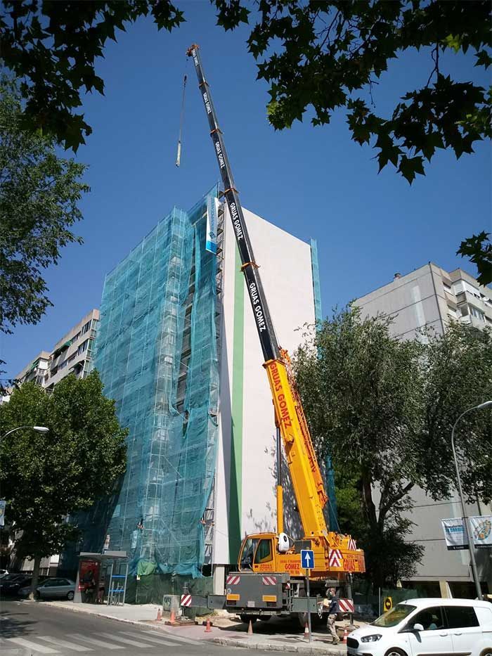 Una gran grúa amarilla está sentada frente a un edificio en construcción.