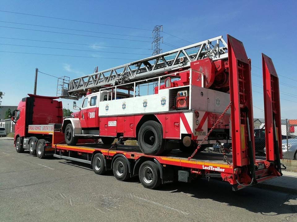 Un camión de bomberos rojo y blanco está siendo transportado en un remolque.