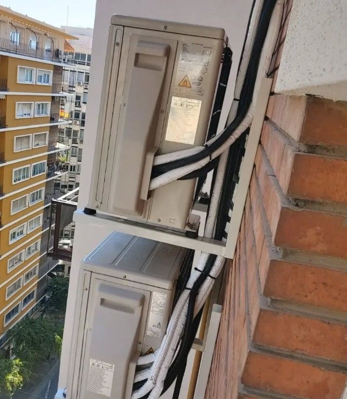 Dos unidades de aire acondicionado exteriores montadas en una pared de ladrillo, con tuberías aisladas.