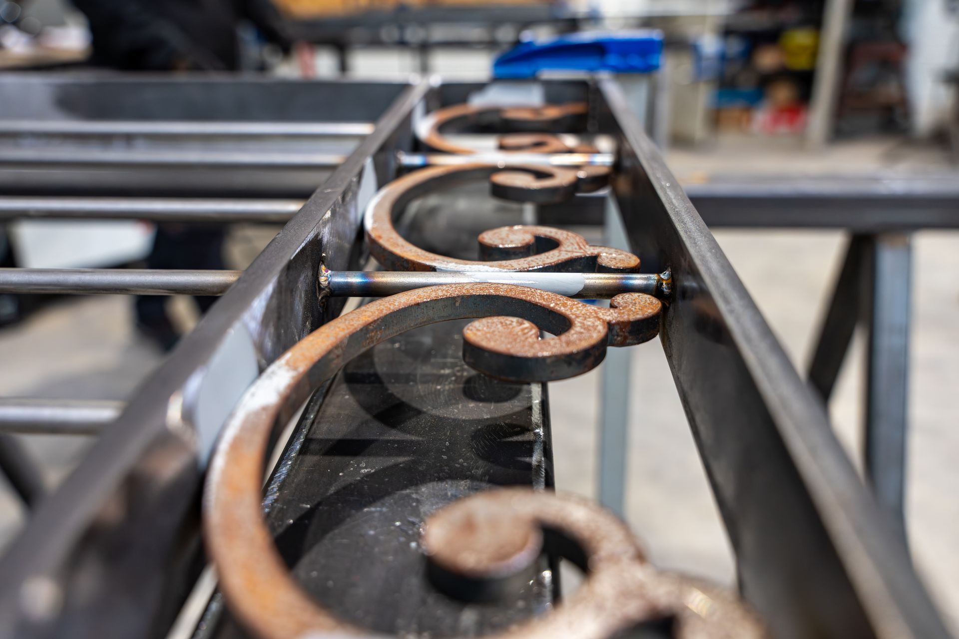 Gros plan sur des volutes en métal sur une rampe noire dans un atelier.