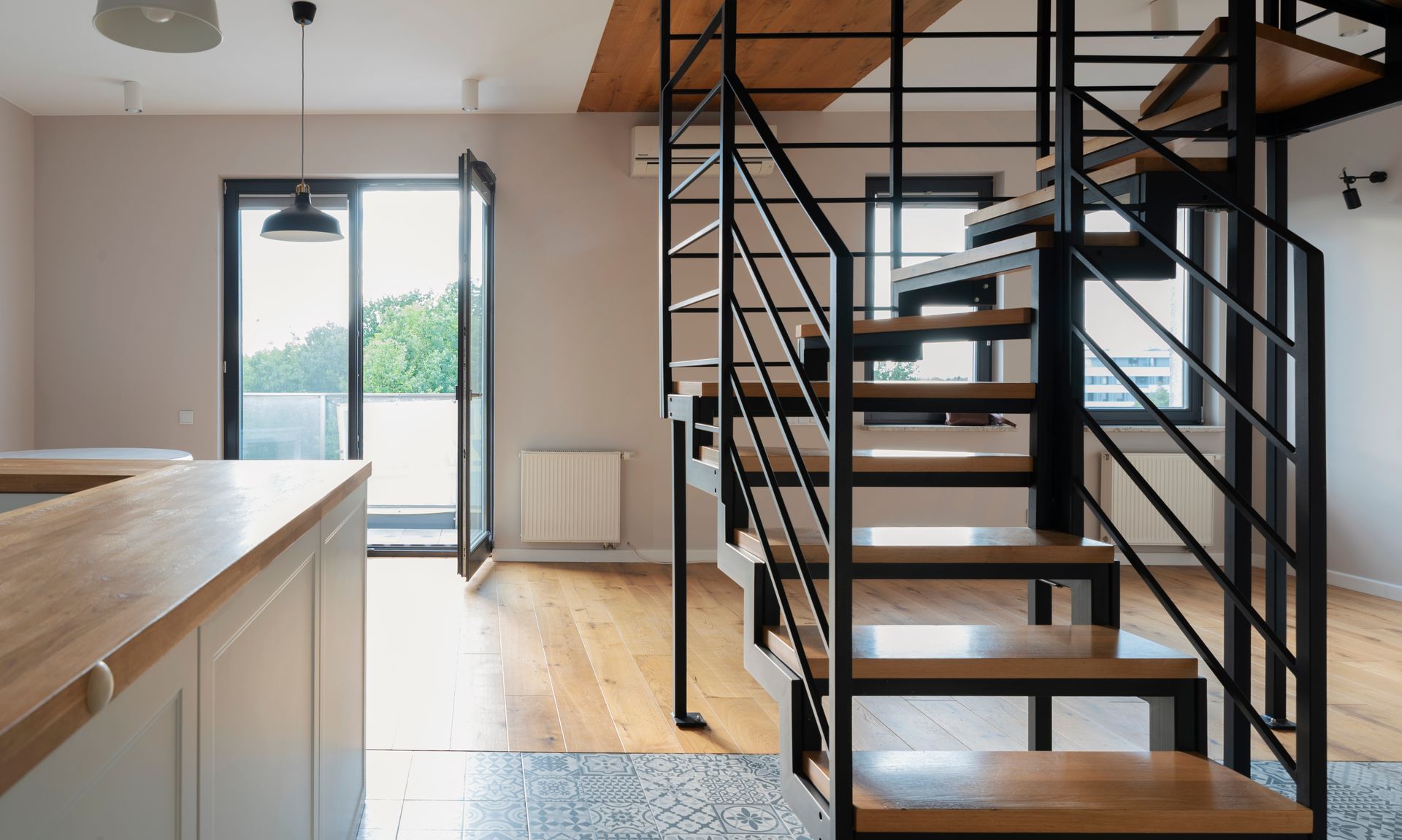 Intérieur de loft moderne avec un escalier en métal noir, des marches en bois, une table à manger et de grandes fenêtres