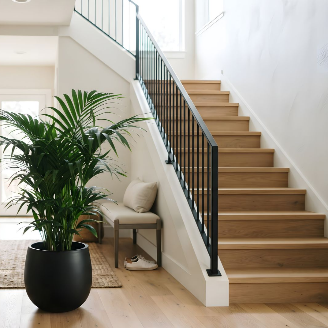 Cage d’escalier lumineuse dans une maison minimaliste, avec une plante en pot et une petite chaise près des marches.