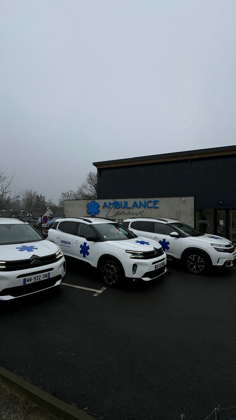 Trois ambulances blanches garées en rang devant notre agence Nor & Via