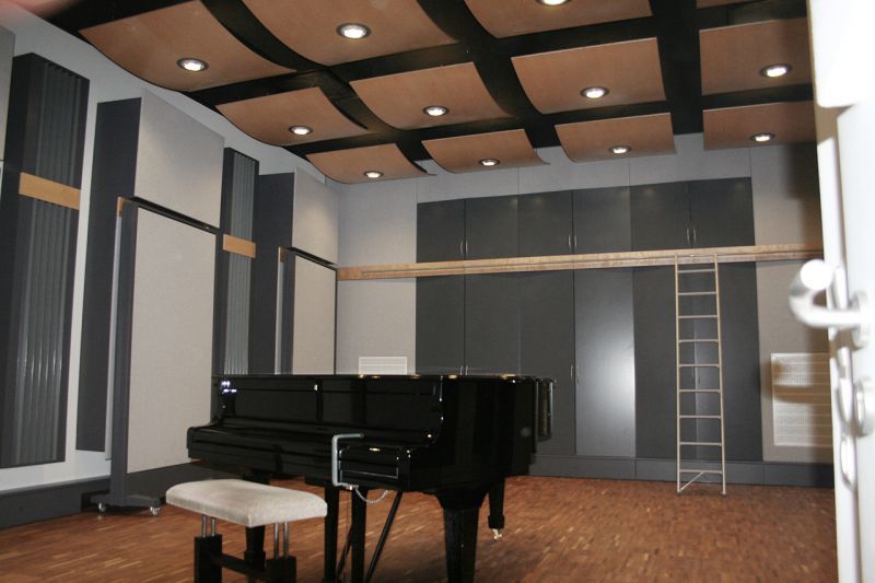 Moderner Musikraum mit Flügel, Holzfußboden, Akustikpaneelen an den Wänden und abgehängter Decke.